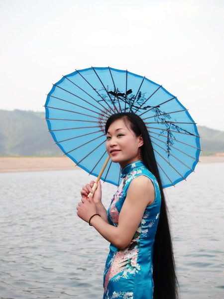 Beautiful girl comb her silky long hair near lake