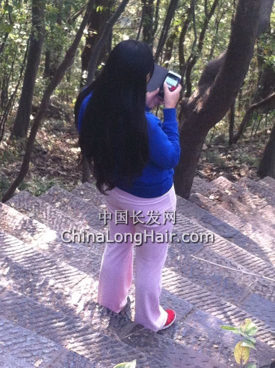 Waist length long hair girl played mobilephone on the way down hill